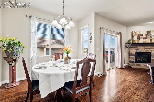 dining space featuring dark hardwood / wood-style flooring, a stone fireplace, and plenty of natural light