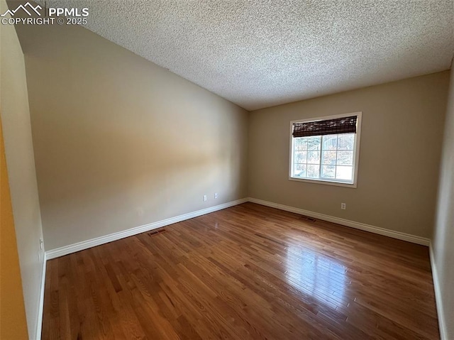 empty room with hardwood / wood-style floors and a textured ceiling