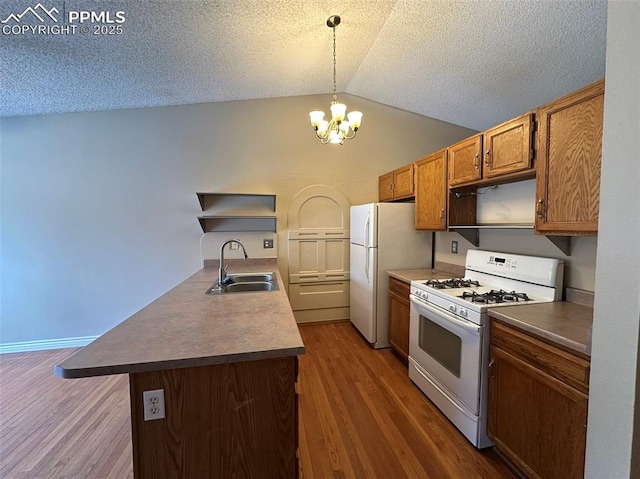 kitchen with lofted ceiling, sink, white appliances, a textured ceiling, and decorative light fixtures