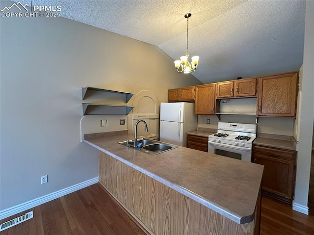 kitchen with pendant lighting, lofted ceiling, sink, kitchen peninsula, and white appliances