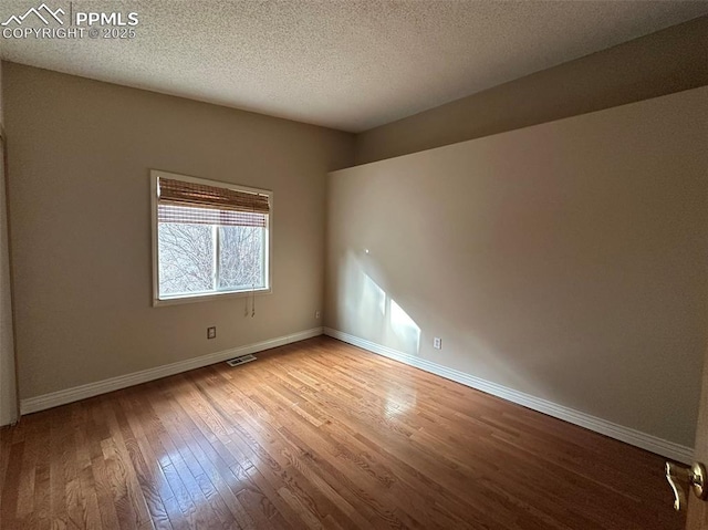 unfurnished room with light hardwood / wood-style floors and a textured ceiling