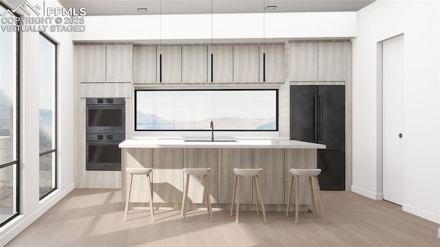 kitchen with sink, multiple ovens, a healthy amount of sunlight, and black fridge