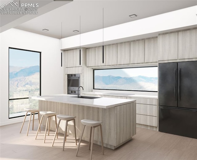 kitchen featuring black fridge, sink, a kitchen island with sink, and a wealth of natural light