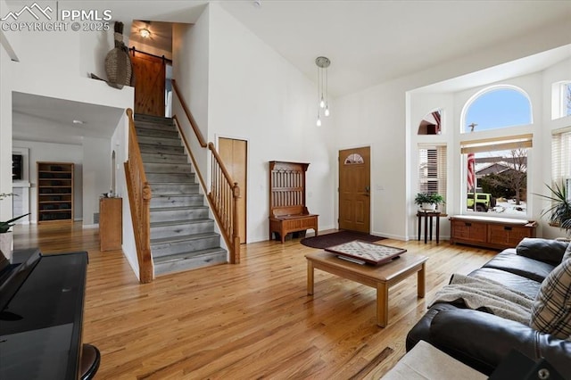 living room with a towering ceiling, a barn door, and light hardwood / wood-style floors