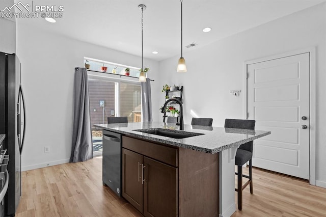 kitchen with sink, a breakfast bar, appliances with stainless steel finishes, a kitchen island with sink, and hanging light fixtures