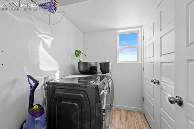 washroom featuring washing machine and dryer and light hardwood / wood-style flooring