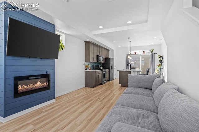 living room with sink, a wealth of natural light, and light wood-type flooring