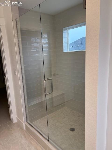 bathroom with a shower stall and tile patterned flooring