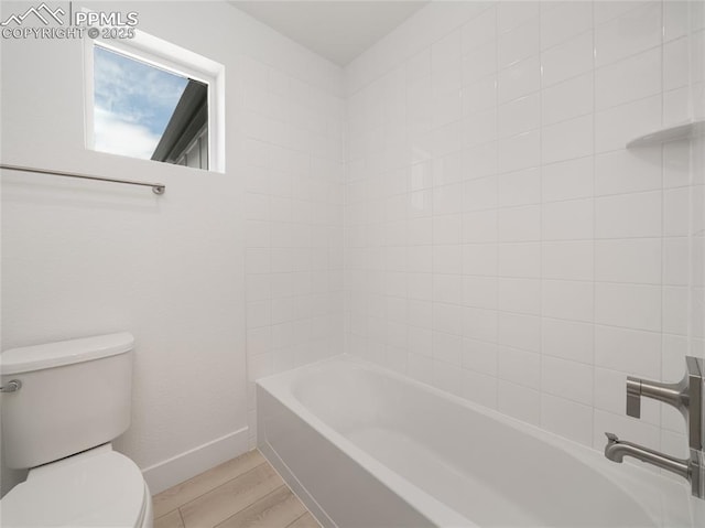 bathroom featuring toilet, shower / bath combination, wood finished floors, and baseboards