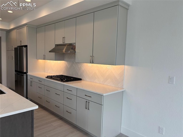 kitchen with stainless steel appliances, under cabinet range hood, decorative backsplash, and gray cabinets