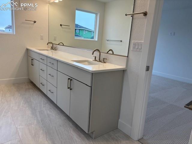full bath featuring double vanity, baseboards, and a sink