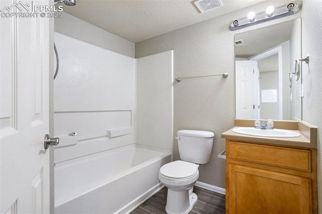 full bathroom featuring hardwood / wood-style floors, washtub / shower combination, vanity, toilet, and a textured ceiling