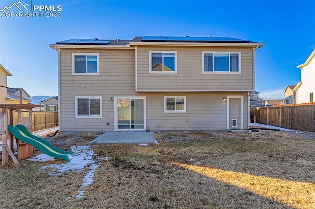 rear view of property featuring a patio and a playground