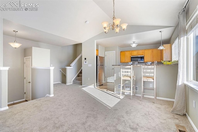 kitchen with stainless steel appliances, vaulted ceiling, and hanging light fixtures