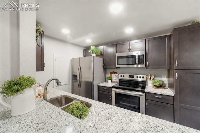 kitchen featuring dark brown cabinetry, appliances with stainless steel finishes, sink, and light stone counters