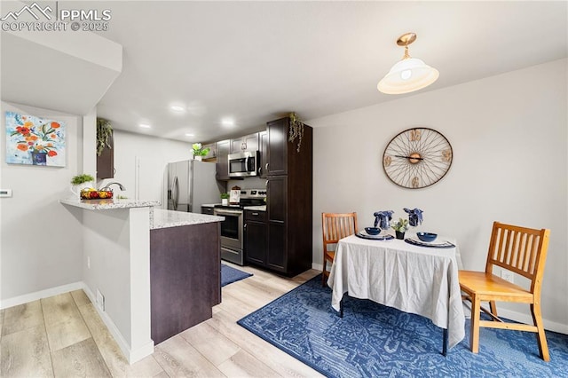 kitchen with dark brown cabinetry, stainless steel appliances, kitchen peninsula, and light hardwood / wood-style flooring