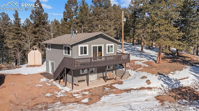 snow covered house featuring a storage unit and a deck