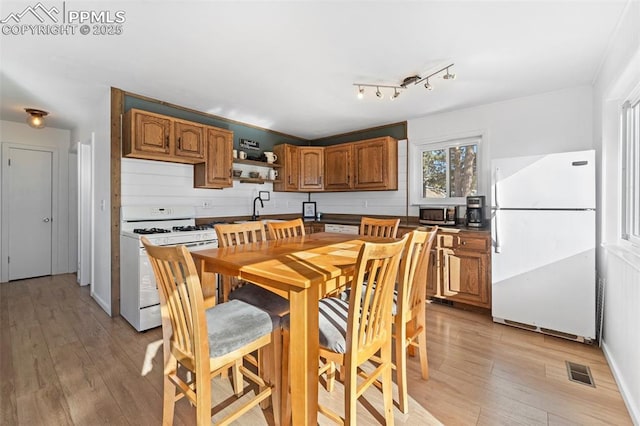 kitchen featuring sink, white appliances, light hardwood / wood-style flooring, and decorative backsplash