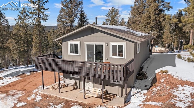 snow covered back of property featuring a patio