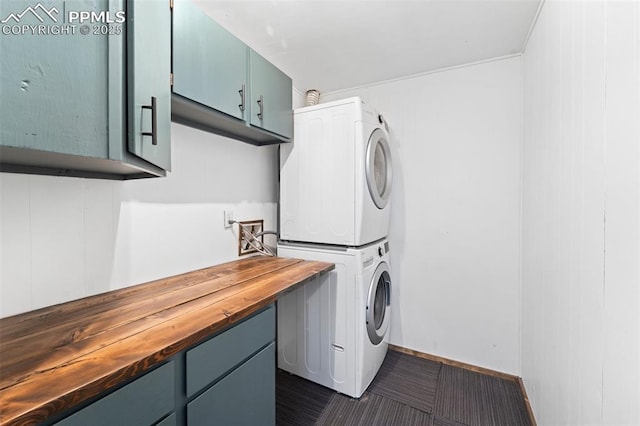 washroom featuring cabinets and stacked washer / dryer