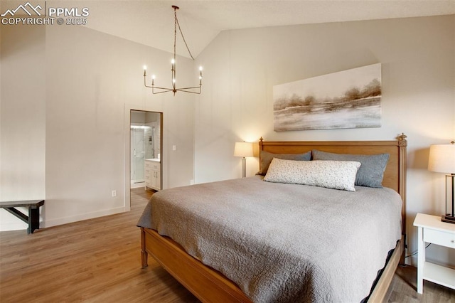 bedroom featuring lofted ceiling, connected bathroom, hardwood / wood-style floors, and a chandelier