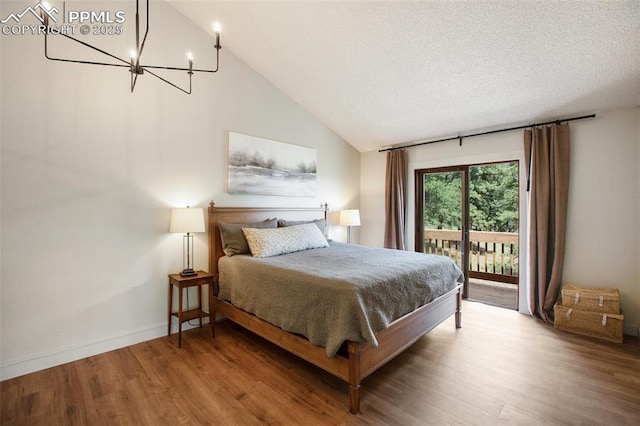 bedroom featuring lofted ceiling, access to exterior, a chandelier, and hardwood / wood-style floors