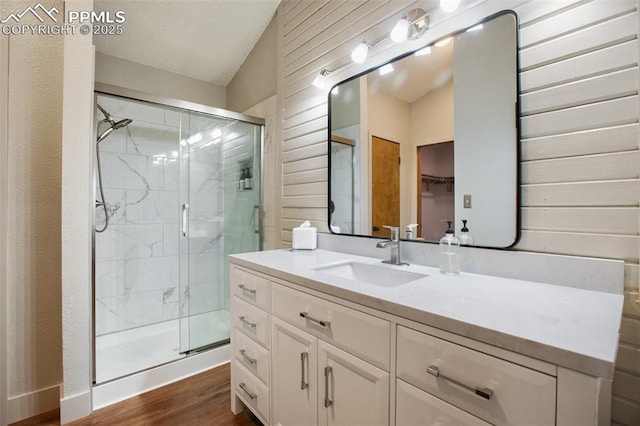 bathroom with a shower with door, vanity, lofted ceiling, and hardwood / wood-style floors