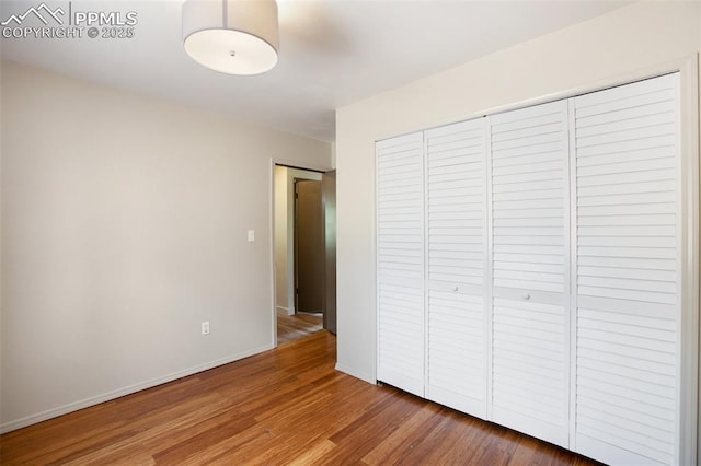 unfurnished bedroom featuring wood-type flooring and a closet