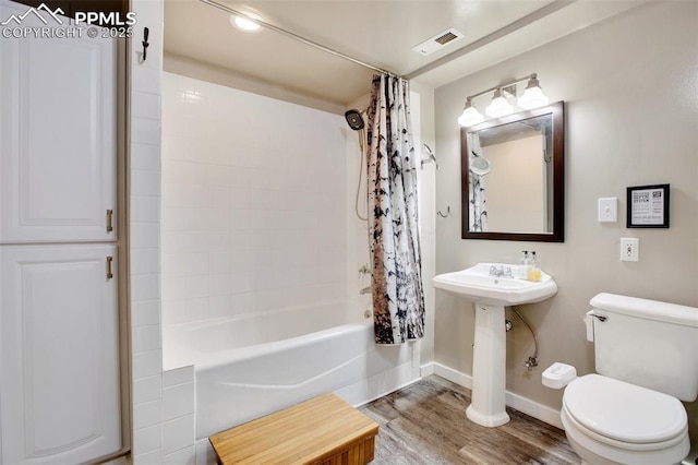 bathroom with hardwood / wood-style floors, shower / tub combo with curtain, and toilet