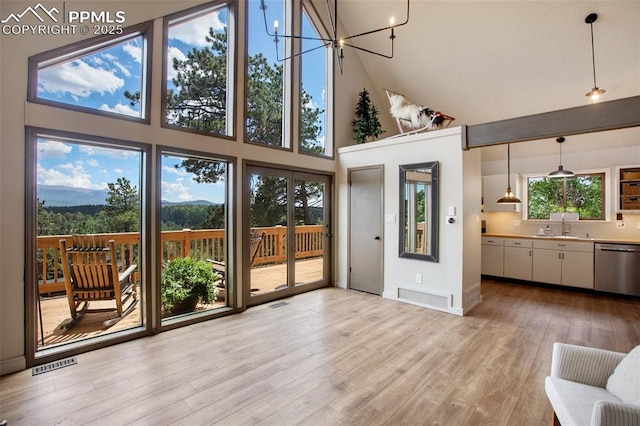 interior space featuring sink, a chandelier, high vaulted ceiling, and light wood-type flooring