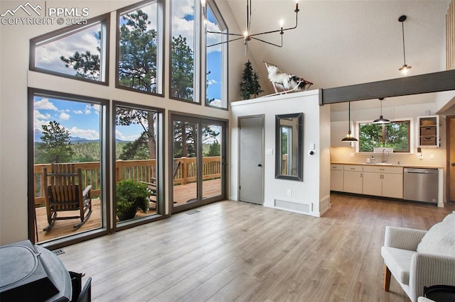 living room featuring sink, high vaulted ceiling, light hardwood / wood-style floors, and a chandelier