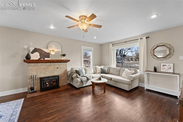 living room featuring dark wood-type flooring, a tile fireplace, and ceiling fan