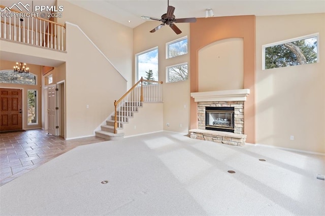 carpeted living room featuring ceiling fan with notable chandelier, a fireplace, and high vaulted ceiling