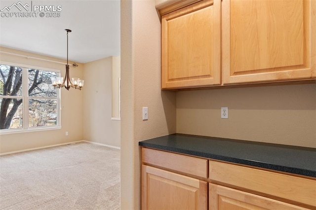 kitchen featuring light brown cabinetry, hanging light fixtures, light carpet, and a chandelier