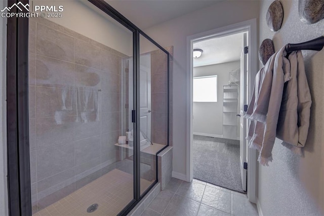 bathroom with a shower with door and tile patterned flooring