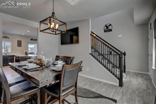 dining space featuring an inviting chandelier, sink, and light hardwood / wood-style flooring