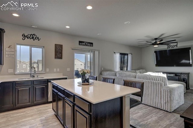 kitchen with ceiling fan, a kitchen island, sink, and light hardwood / wood-style floors
