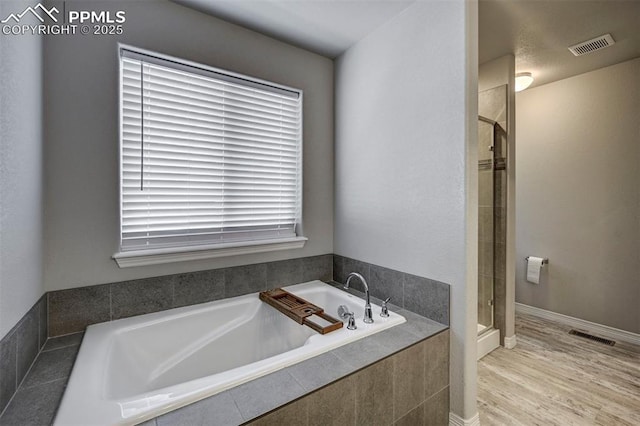bathroom featuring hardwood / wood-style flooring and separate shower and tub