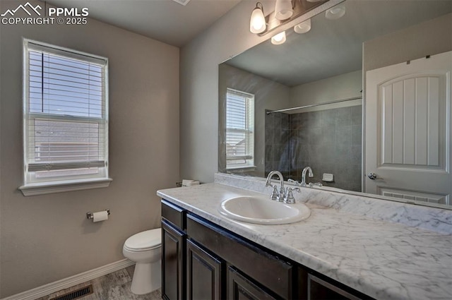 bathroom featuring vanity, hardwood / wood-style floors, toilet, and a tile shower