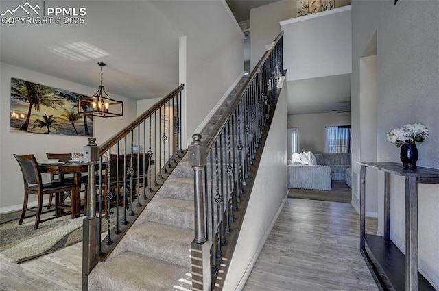 staircase with hardwood / wood-style flooring, a chandelier, and a towering ceiling