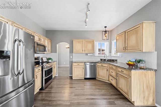 kitchen featuring sink, appliances with stainless steel finishes, tasteful backsplash, decorative light fixtures, and dark stone counters