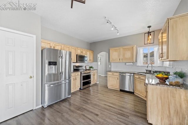 kitchen with appliances with stainless steel finishes, decorative light fixtures, sink, dark stone countertops, and light brown cabinets