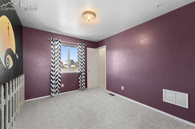 carpeted empty room with a textured ceiling