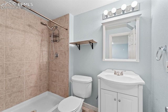 bathroom with vanity, a tile shower, and toilet