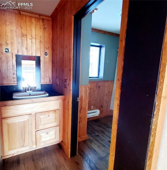 bathroom featuring baseboard heating, vanity, wooden walls, and hardwood / wood-style flooring