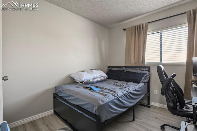 bedroom featuring light wood-type flooring and a textured ceiling