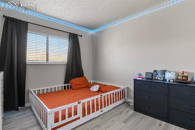 bedroom featuring a textured ceiling and light hardwood / wood-style flooring