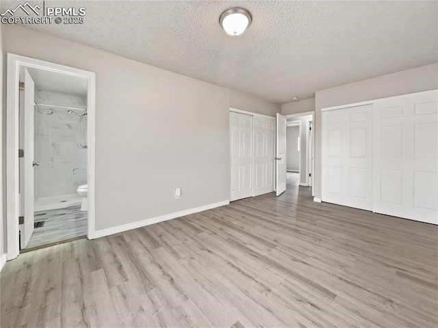 unfurnished bedroom with connected bathroom, a textured ceiling, and light hardwood / wood-style floors