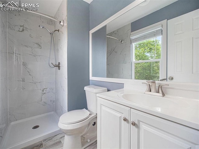 bathroom with vanity, tiled shower, and toilet