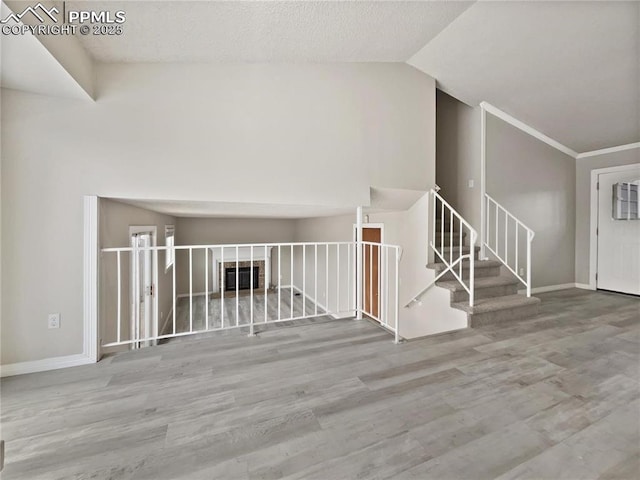 interior space with vaulted ceiling, crown molding, and light hardwood / wood-style floors